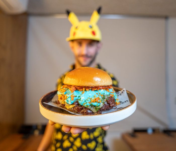 Iván Villarij mostrando una hamburguesa creativa y colorida de estilo gourmet